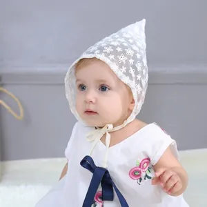 Close-up of white lace baby bonnet with floral embroidery and pointed top design
