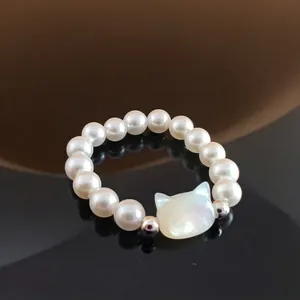 Detail of beaded pearl ring featuring a white shell cat charm and silver accents