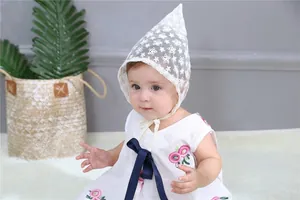 Detail of baby lace bonnet and embroidered dress with a blue satin bow for girls