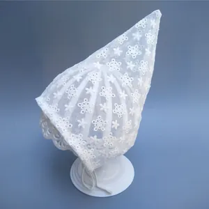 Macro shot of white lace pixie bonnet featuring delicate floral embroidery and ties