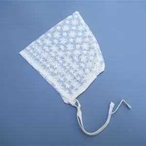 Close-up of baby lace bonnet featuring delicate floral embroidery and pointed top design