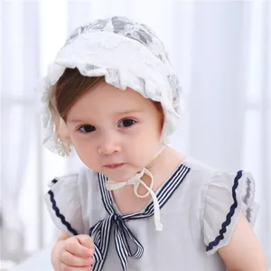 Detailed close-up of delicate floral embroidery on a white baby lace bonnet