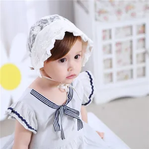 Detailed view of white floral lace baby bonnet with scalloped edges and ties