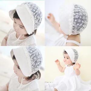 Detail of white floral lace baby bonnet with ruffle edges and delicate ribbon ties
