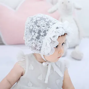 Close-up of white lace baby bonnet with floral patterns and delicate mesh ruffle edge