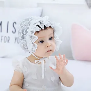 Detailed view of white lace baby bonnet with delicate floral patterns and ruffled edges