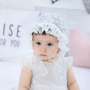 Detail of baby white lace bonnet with ruffled edges and 3D heart dress for newborn photography