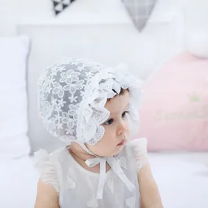 Close-up of baby white lace bonnet with floral mesh embroidery and ruffled edges