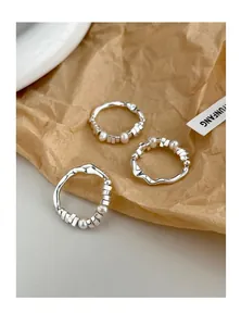 Macro shot of S925 sterling silver wavy rings set with freshwater pearls on brown paper
