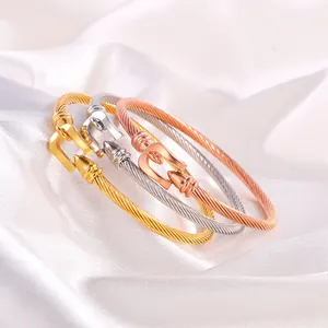 Close-up of three braided titanium steel cable bracelets with horseshoe buckles in gold, silver, and rose gold