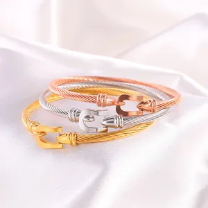 Macro shot of gold, silver, and rose gold woven steel horse-shoe buckle bracelets