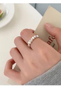Macro shot of S925 silver square beads and white freshwater pearl band on a finger