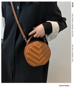 Brown quilted round crossbody bag shown with a black coat for a stylish daily look