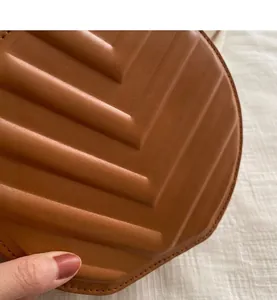 Detailed macro view of caramel brown leather handbag with V-shaped quilted pattern