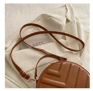 Detailed close-up of brown quilted crossbody bag with golden zipper and leather strap
