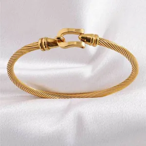 Close-up of golden cable bracelet with horseshoe buckle on white silk background