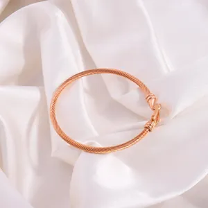 Detail of rose gold cable bracelet featuring hook closure on white silk background