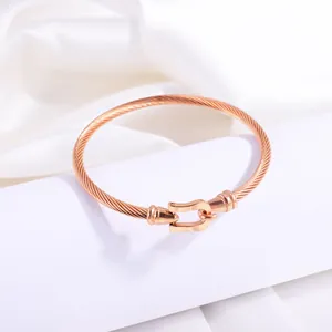 Detail of rose gold braided cable bracelet featuring a polished U-shaped horse hoof clasp