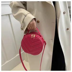 Detailed view of magenta round crossbody bag with chevron quilting and gold zippers