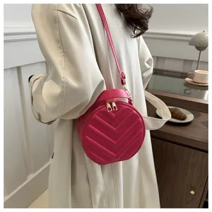 Detail of rose red round crossbody bag with V-shaped quilting and gold zipper