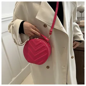 Detail of rose red round crossbody bag featuring V-shaped quilted faux leather pattern
