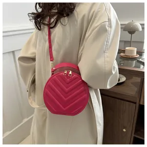 Detail of rose red round crossbody bag with V-shaped quilting and golden zippers