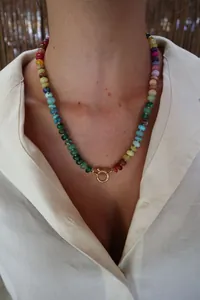Detail einer bunten Perlenkette mit goldenem Federverschluss an einem Model