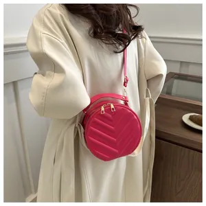 Detail of round magenta crossbody bag with chevron quilting and dual gold zippers