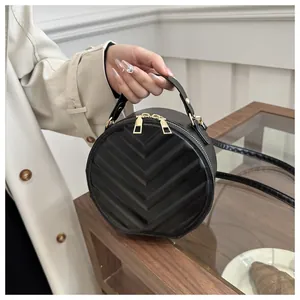 Detail of black round crossbody bag with V-shaped quilting and gold hardware zipper