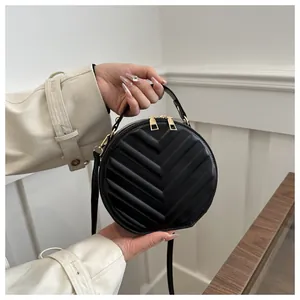 Detail of black chevron quilted round crossbody bag with gold hardware and top handle