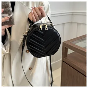 Detail of round black quilted handbag with golden zipper and leather top handle