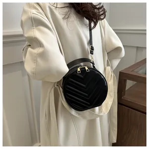 Detail of black round crossbody bag with chevron quilting and golden zippers