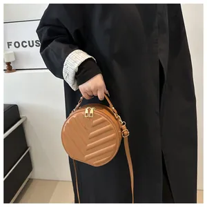 Close-up of brown round crossbody bag with V-quilted faux leather and gold hardware