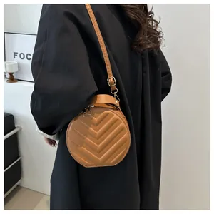 Detail of a brown circular crossbody bag featuring V-shaped quilted leather texture