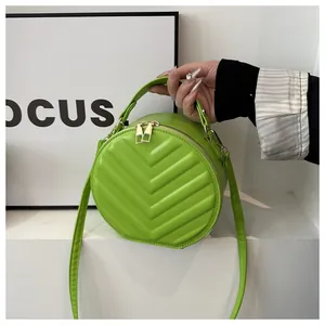 Detail of neon green round crossbody bag featuring chevron quilting and gold zippers