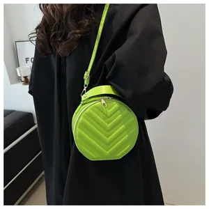 Detail of green quilted round crossbody bag with top handle and V-shaped stitching