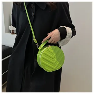 Detail shot of a lime green round crossbody bag featuring V-shaped quilting and a handle