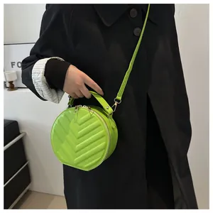 Close-up of quilted neon green round crossbody bag styled with a black trench coat