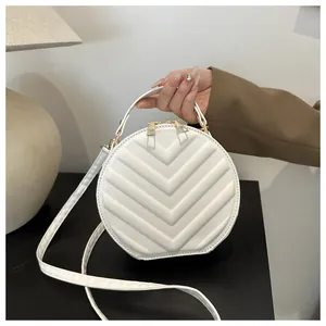 Detail of white round crossbody bag with V-shaped embossed texture and metal zipper