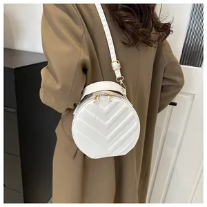 Close-up of a white round crossbody bag with V-quilted faux leather and gold zippers