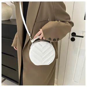 Detail of white quilted round crossbody bag with gold hardware and top handle