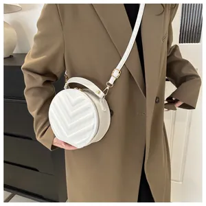 Close-up of a white quilted round handbag with gold hardware and stylish top handle