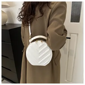 Chic white round quilted crossbody bag with V-pattern stitching shown on model coat