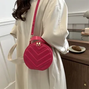 Fashionable magenta round crossbody bag with V-quilted texture and gold zippers