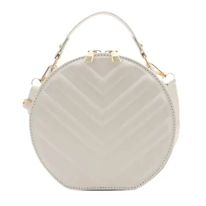 Minimalist round crossbody bag in pearl white featuring V-shaped quilted texture and gold hardware