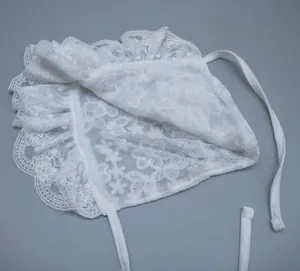 Close-up of baby lace bonnet featuring intricate floral hollow patterns and scalloped edges