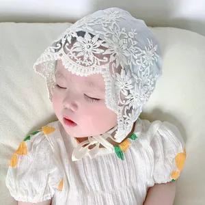 Close-up of light blue baby lace bonnet with white floral embroidery and chin straps