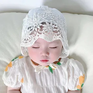 Close-up of white lace baby bonnet featuring floral embroidery and adjustable straps