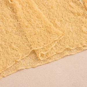 Close-up of yellow floral lace fabric with intricate mesh texture for summer dresses