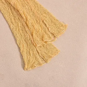 Close-up of light yellow lace mesh fabric with intricate breathable floral texture